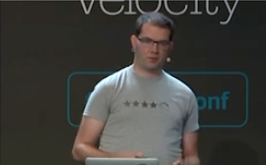 Small blurry picture of a conference speaker wearing a shirt with four stars and a horse